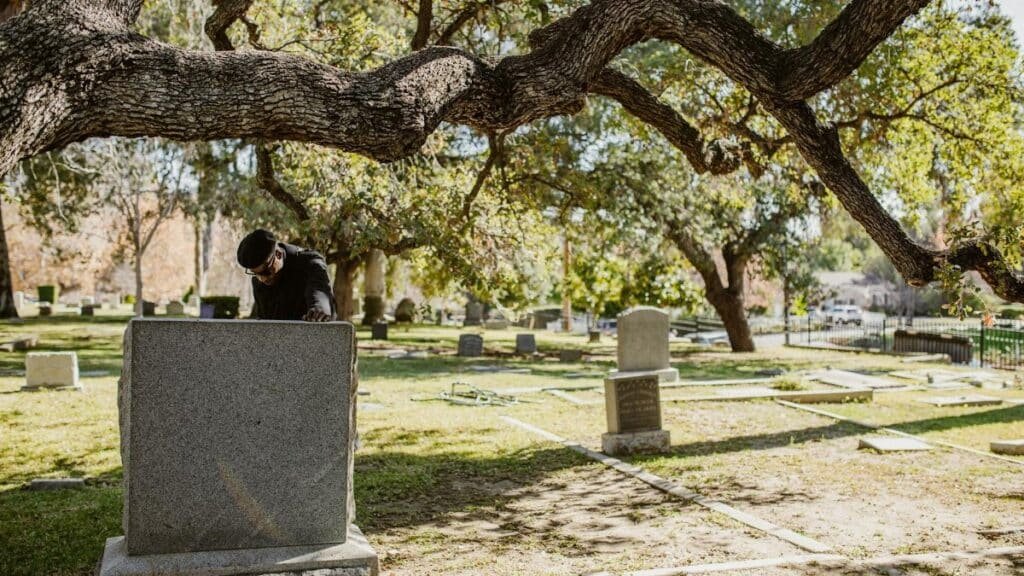 A man stands alone in a peaceful cemetery, reflecting on life and loss.