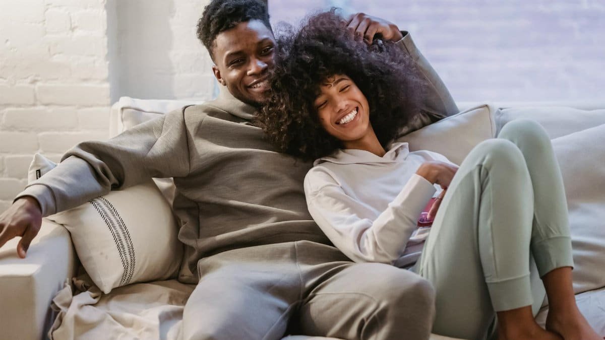 Young couple enjoying a cozy moment at home, smiling and relaxed on the sofa.