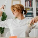 Woman in living room joyfully counting cash, expressing financial success and happiness.