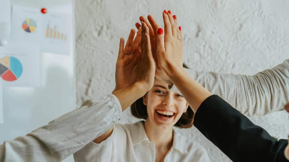 Happy colleagues high-fiving in a meeting, showcasing teamwork and success.
