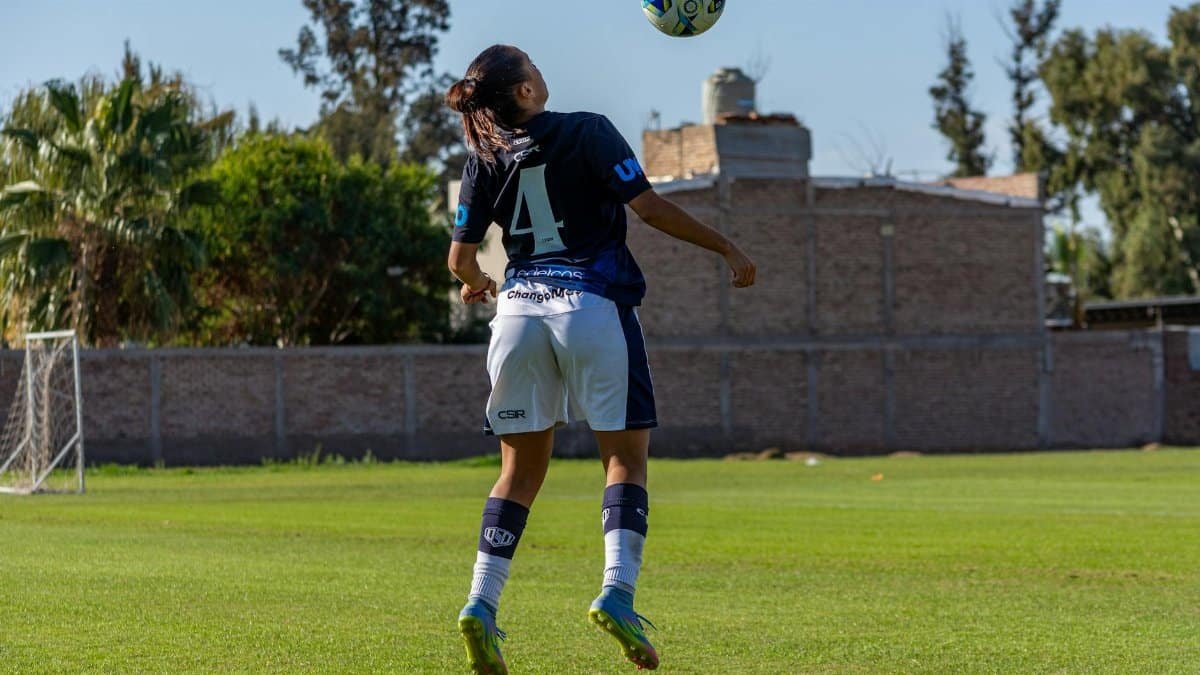 Football player back view heading the ball during practice on a sunny day.