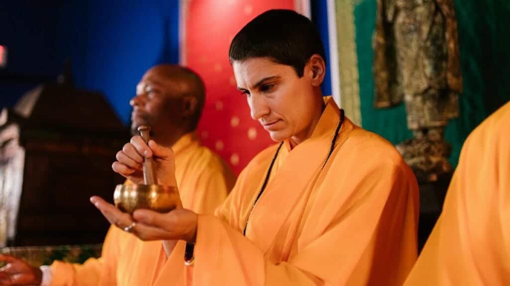 Buddhist monks meditating with a Tibetan singing bowl during a traditional ceremony.
