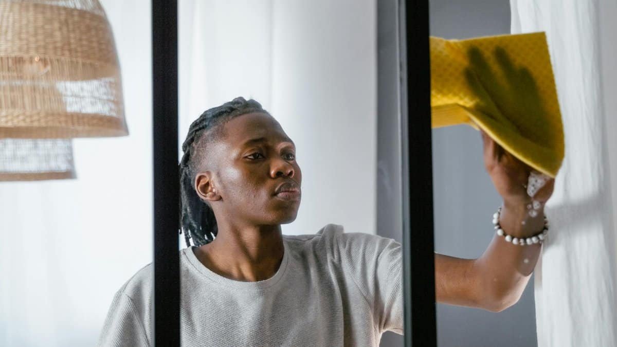 A man cleaning a window with a yellow towel, focusing on indoor chores.
