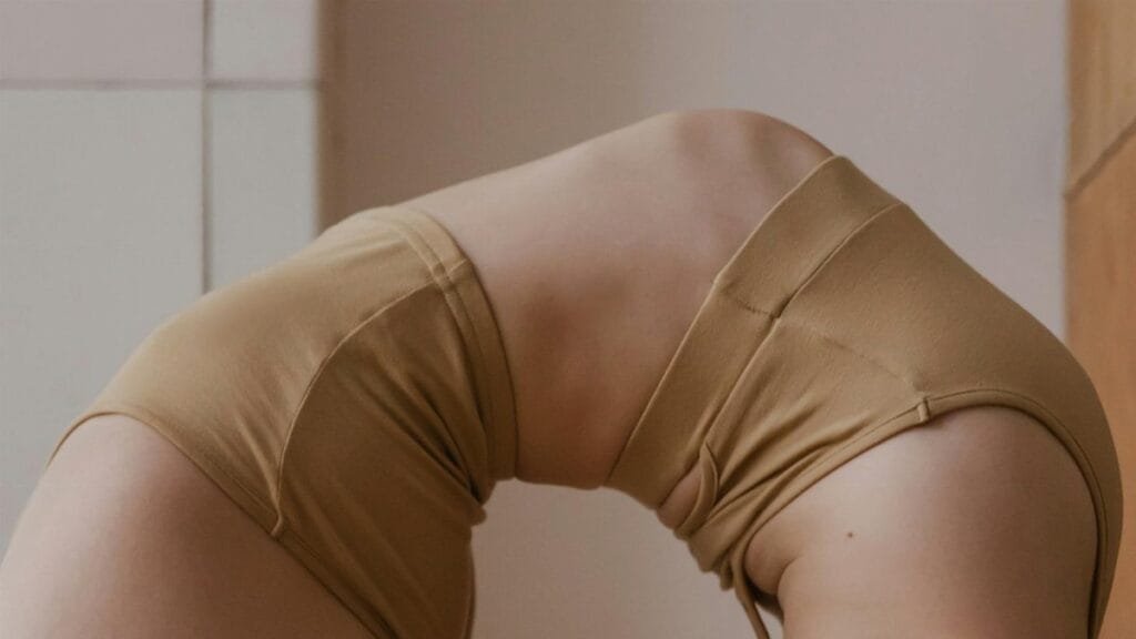 A close-up of an athletic person demonstrating a flexible yoga pose indoors, highlighting movement and strength.