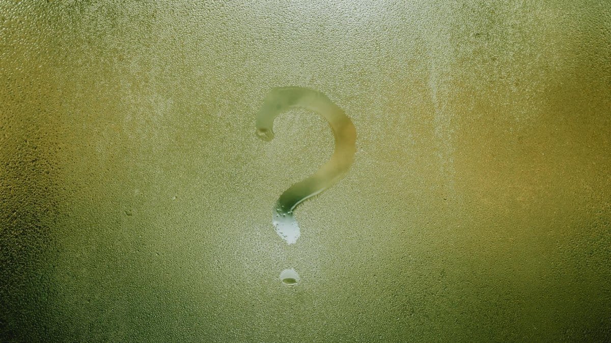 A question mark drawn on foggy glass, evoking curiosity and mystery.
