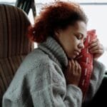 A peaceful moment of a woman sleeping in a campervan, wrapped in a cozy sweater during a winter road trip.