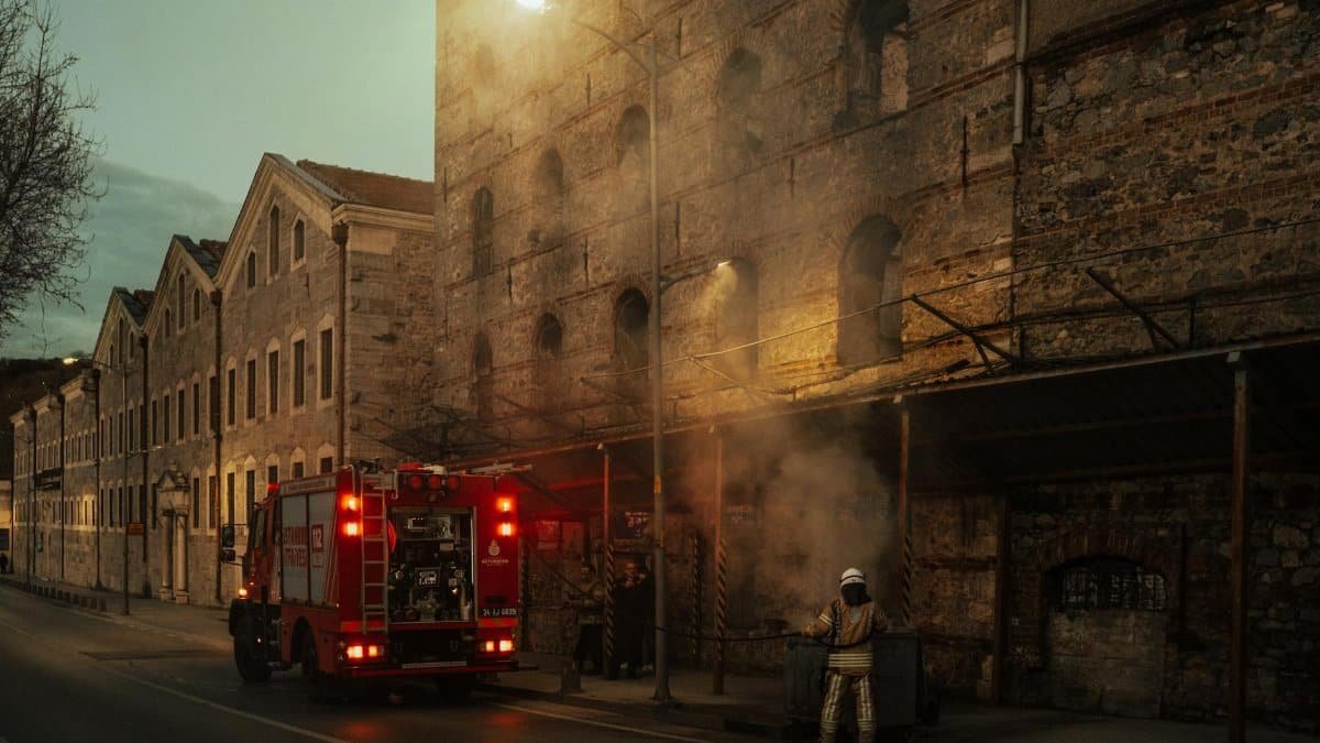 Firefighters managing smoke outside a historic building at dusk. Urban emergency response in action.