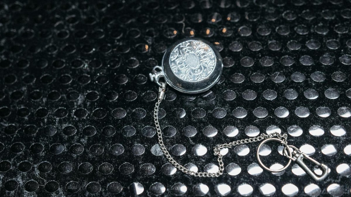 Ornate silver locket with chain, elegantly displayed on black textured background. Perfect for themes of elegance and mystery.