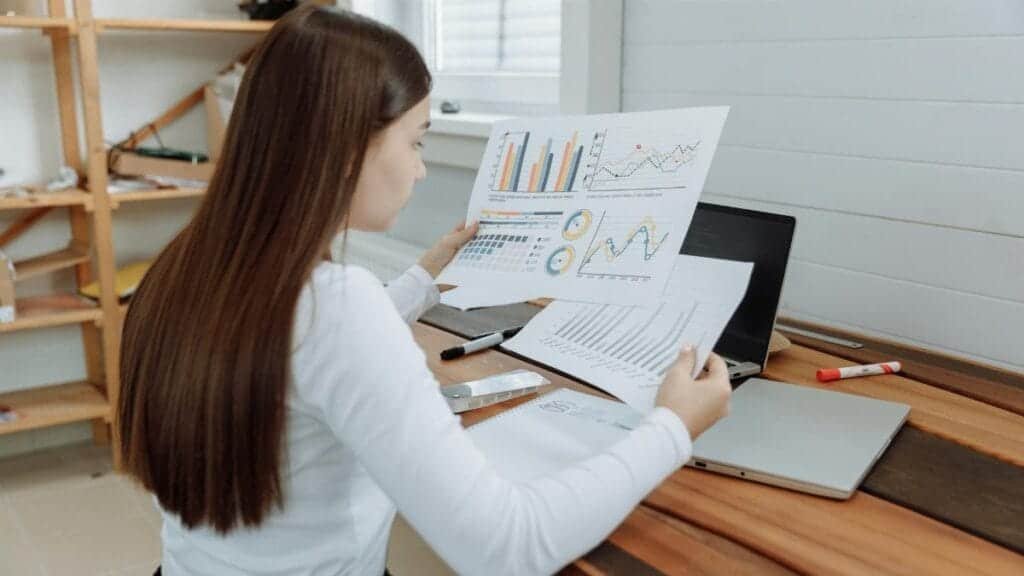 Woman reviewing business charts in a home office setting, showcasing remote work lifestyle.