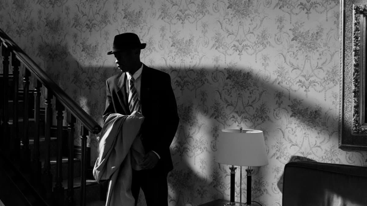 A black and white scene of a detective in a vintage interior, exuding mystery and intrigue.
