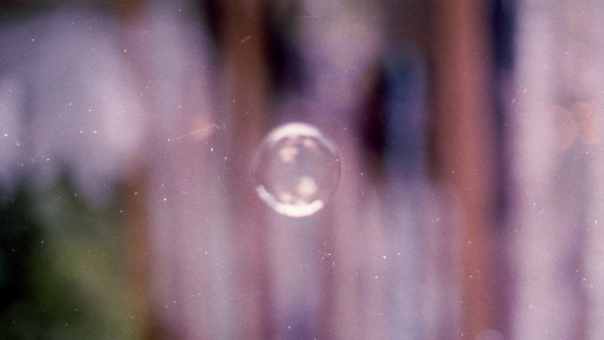 Ethereal film photograph capturing a single bubble surrounded by a dreamy blur.