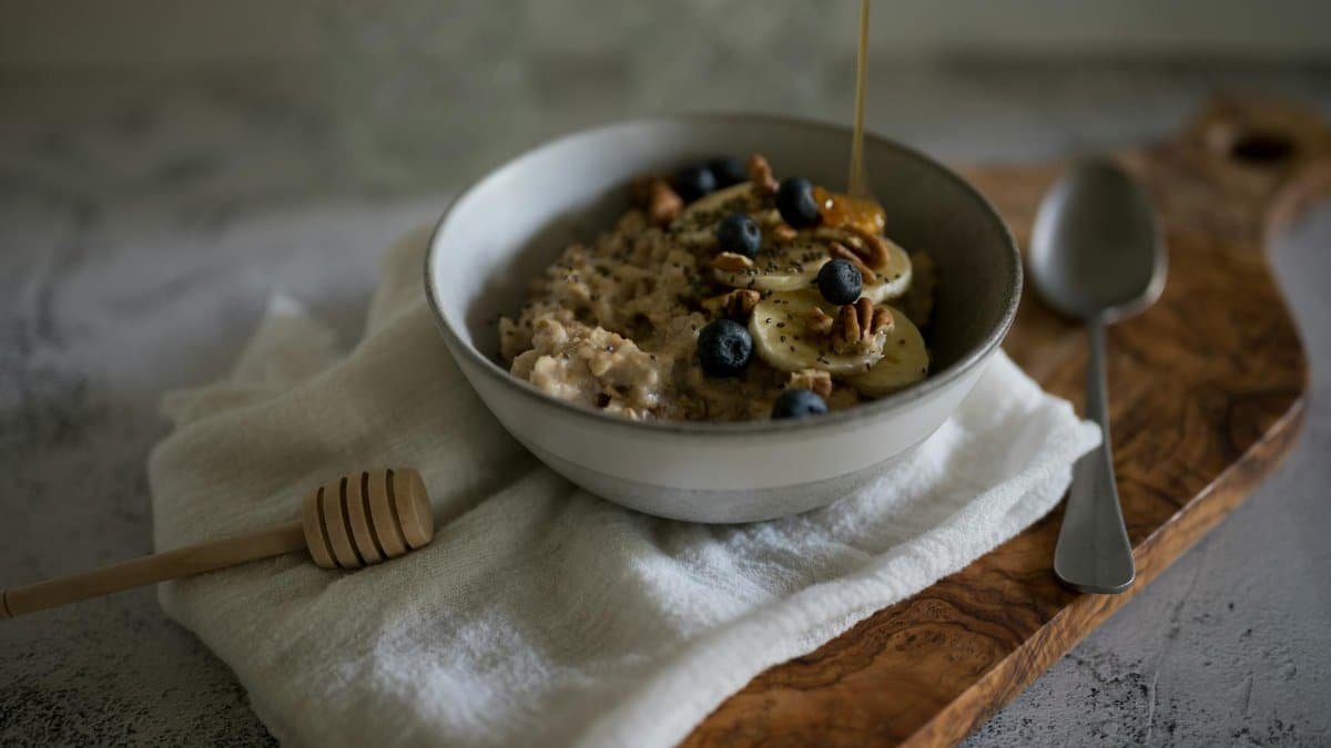 A delicious and nutritious oatmeal bowl with bananas, blueberries, walnuts, and honey.