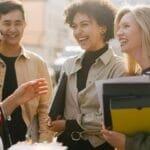 Group of adults laughing and conversing outdoors, capturing a joyful and diverse work environment.