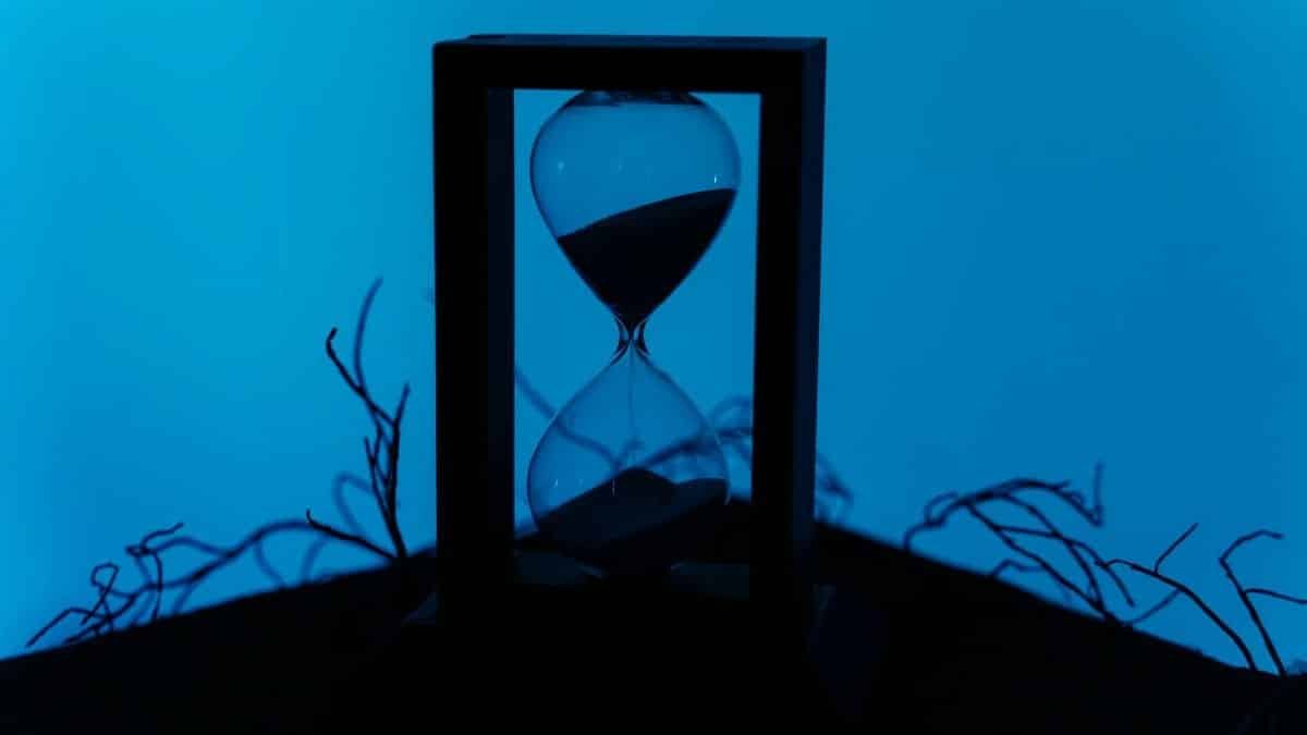A silhouette of an hourglass set against a vivid blue background, highlighting the passage of time.