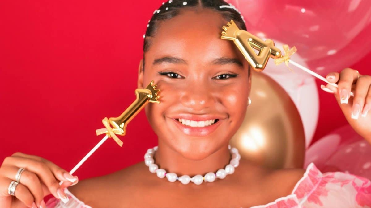 Cheerful young woman celebrating birthday with festive balloons in a studio setting.