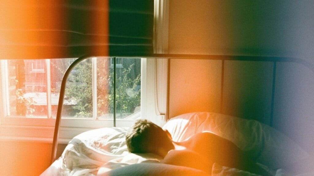 A man peacefully sleeping in a London bedroom, bathed in soft morning light.