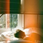 A man peacefully sleeping in a London bedroom, bathed in soft morning light.