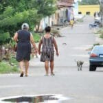 A family walks along a peaceful residential street, showcasing everyday life in a town.
