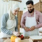 A couple prepares food together in a modern kitchen, showcasing love and partnership.
