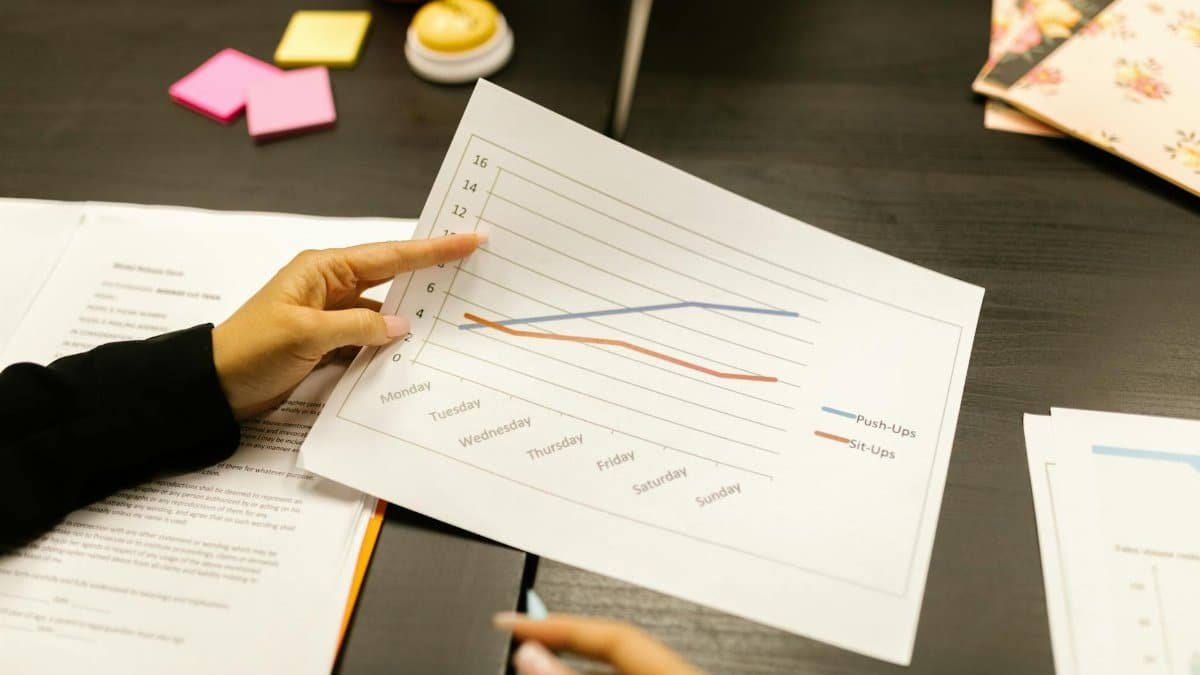 Close-up of hands analyzing a graph during an office meeting, highlighting fitness progress.