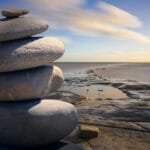 A serene stack of stones on the rocky seashore during a peaceful sunrise, embodying balance and zen.