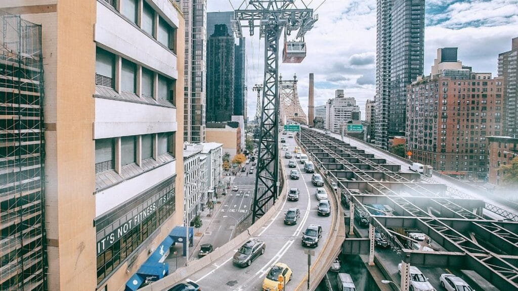 Modern city with multistory residential buildings located near busy asphalt roads with cars inder cloudy sky