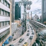 Modern city with multistory residential buildings located near busy asphalt roads with cars inder cloudy sky