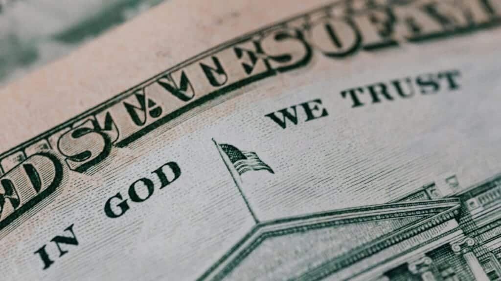 Closeup of ten dollar with inscription In God We Trust bill placed on table with different money
