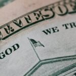 Closeup of ten dollar with inscription In God We Trust bill placed on table with different money