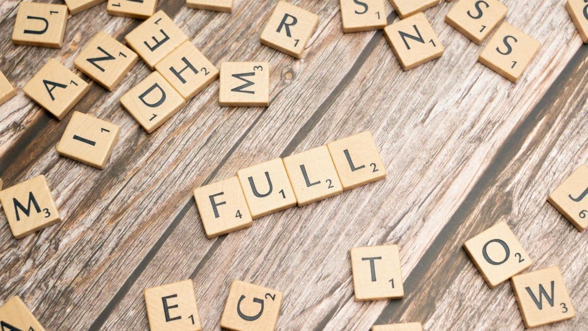 Scattered letter tiles on wood with the word 'FULL' spelled out, conveying abundance.