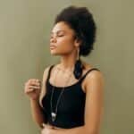 Serene young woman practicing aromatherapy with incense stick indoors, promoting wellness.