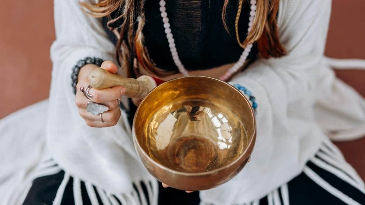 A woman holding a singing bowl, engaging in a peaceful meditation practice.