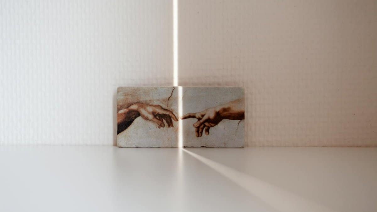 Minimalist photo of Michelangelo's Creation of Adam with dramatic lighting and shadows.