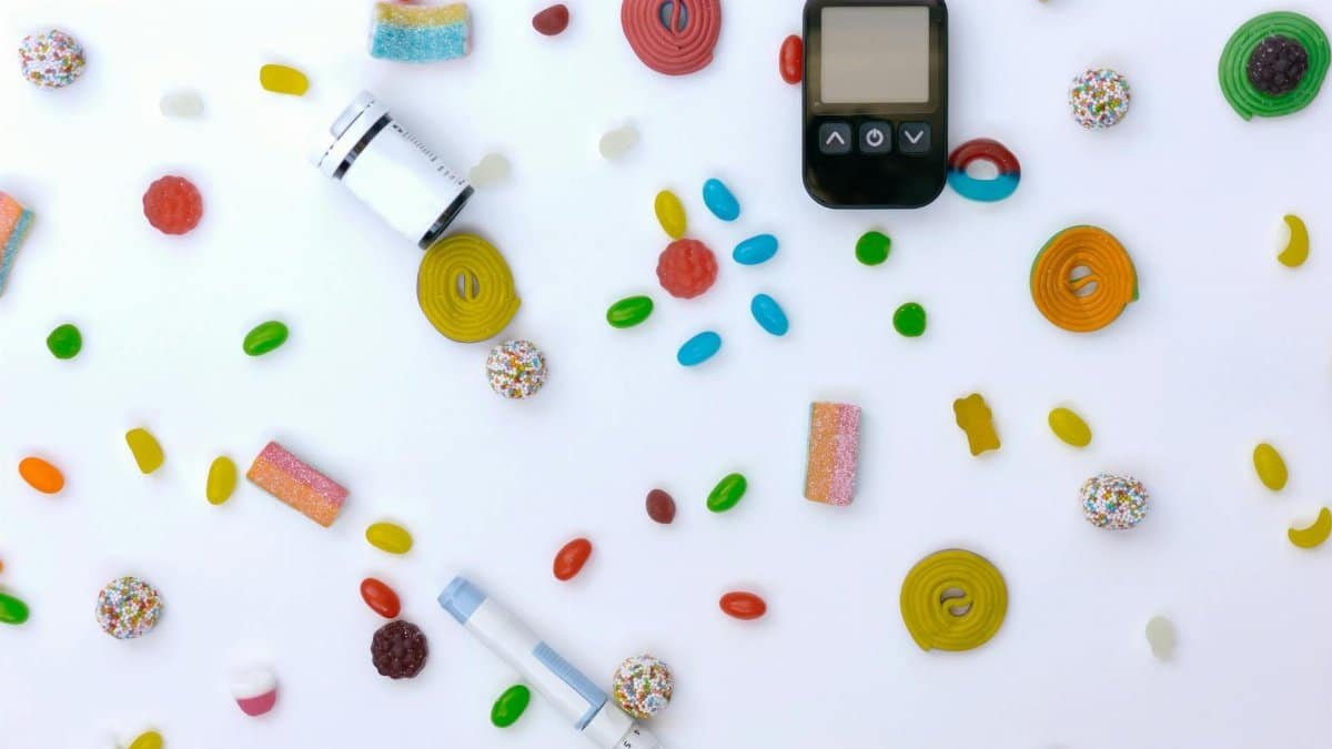 Scattered candies with glucose meter and syringe indicating diabetes and healthcare.