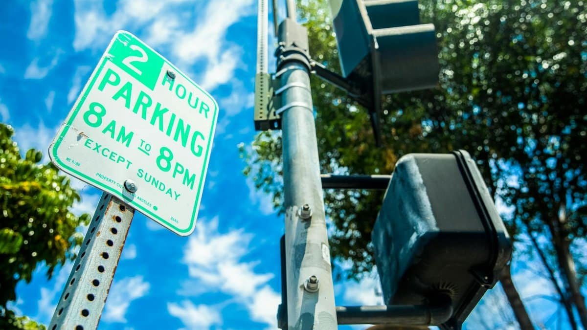 Close-up of a parking sign next to a traffic light in a sunny USA street.