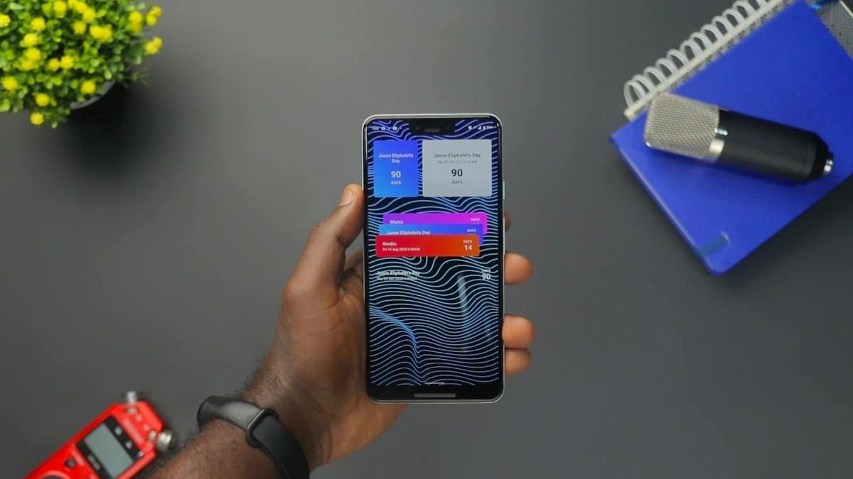 Close-up of a hand holding a smartphone displaying colorful notifications on a black surface.