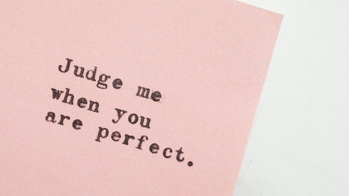 Close-up of an inspirational quote on pink paper, offering a message of judgment and perfection.