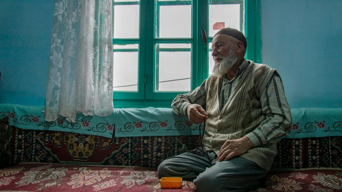 An elderly man sits by a traditional window in Ağırnas, Kayseri, Türkiye.