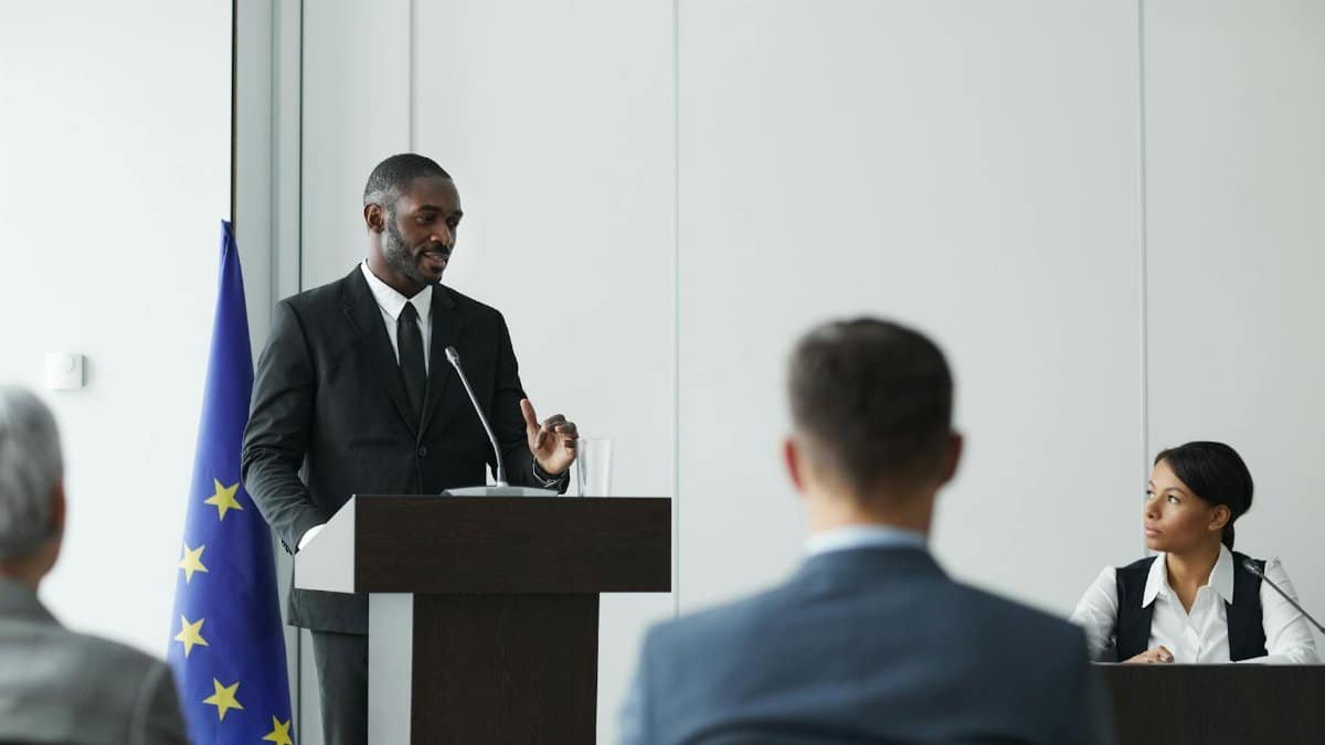 Formal business meeting with diverse speakers in a conference room.