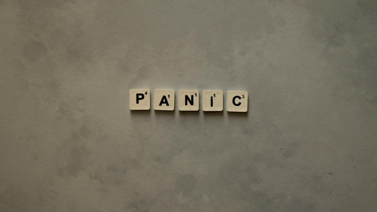 Scrabble tiles forming the word 'Panic' on a simple neutral background, symbolizing anxiety.