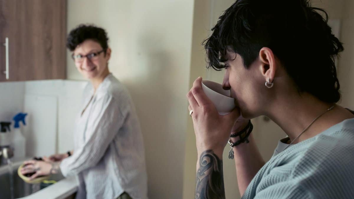 Two friends enjoying a casual conversation over coffee in the kitchen.