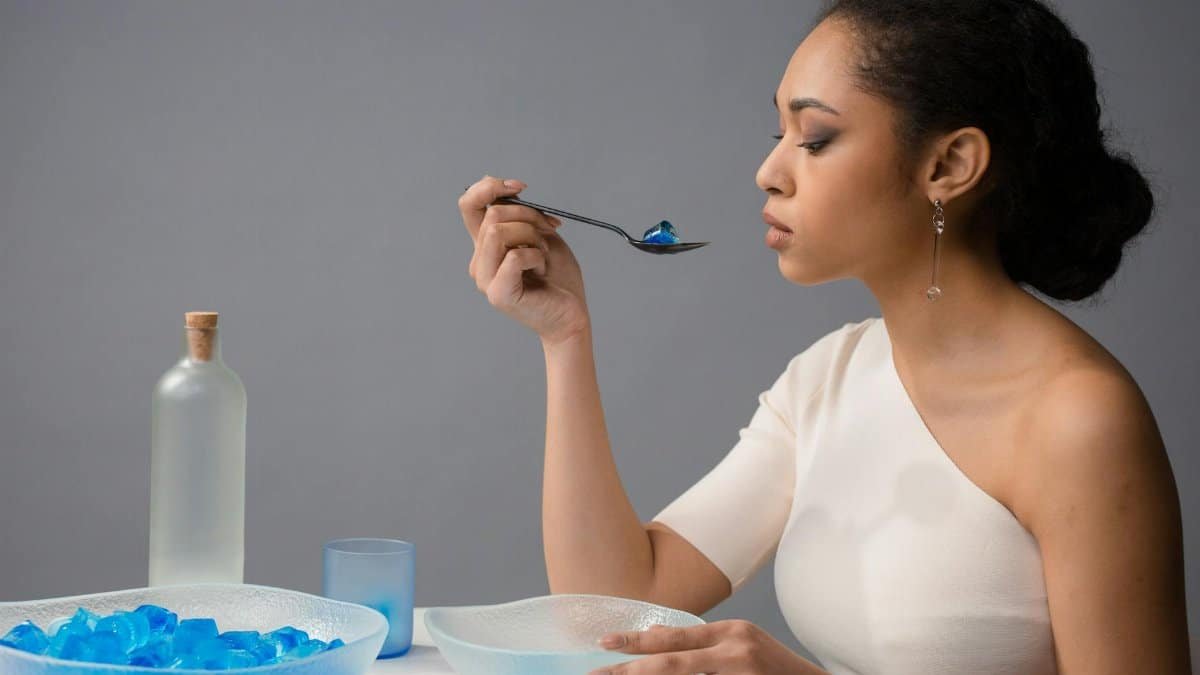 Woman elegantly savoring blue gelatin dessert in studio, exuding grace and style.