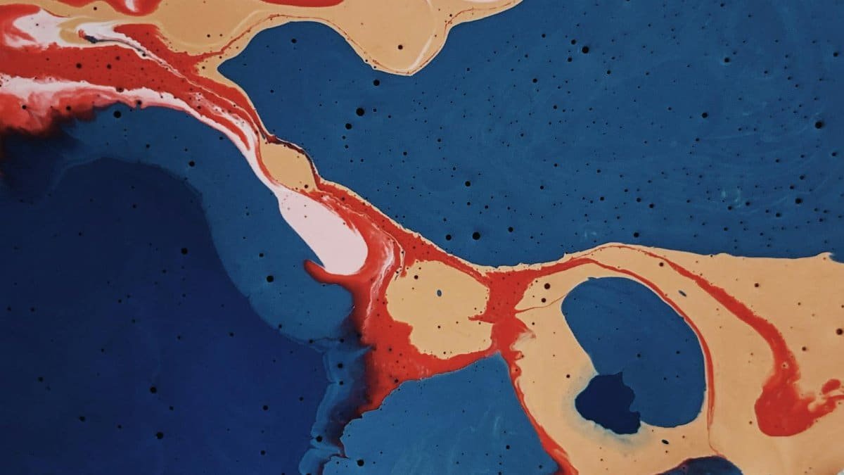 Vibrant abstract painting showcasing bold blue, red, and beige colors with fluid patterns and textures.