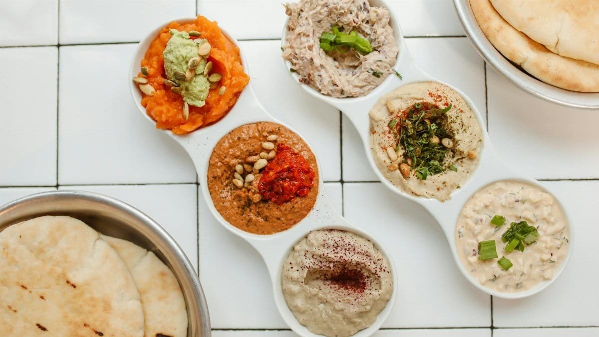 Middle Eastern mezze platter with assorted dips and pita bread.