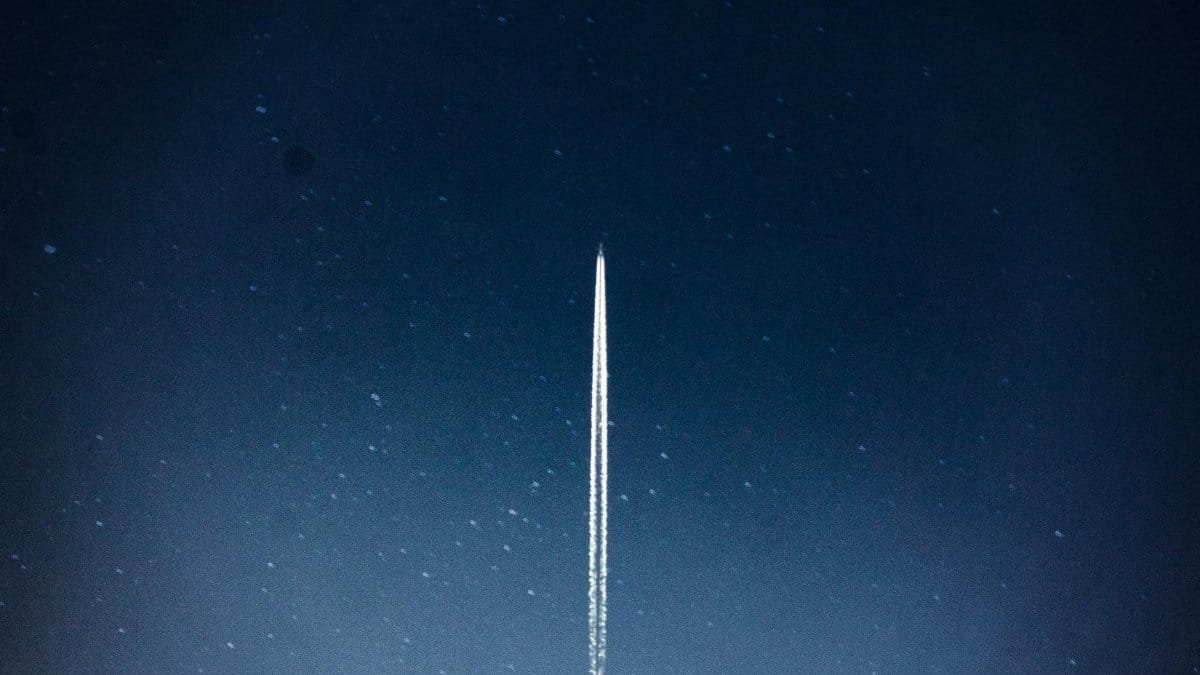 A rocket streaks through a starry night, leaving a trail in outer space.