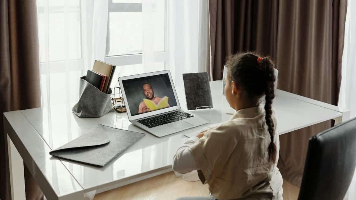Young girl engaged in a virtual learning session at home with a teacher on video call.