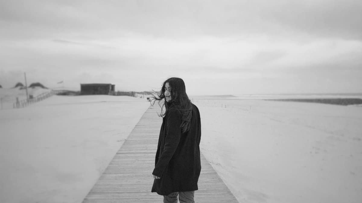Black and white photo of a woman walking on a sandy beach in Portugal.