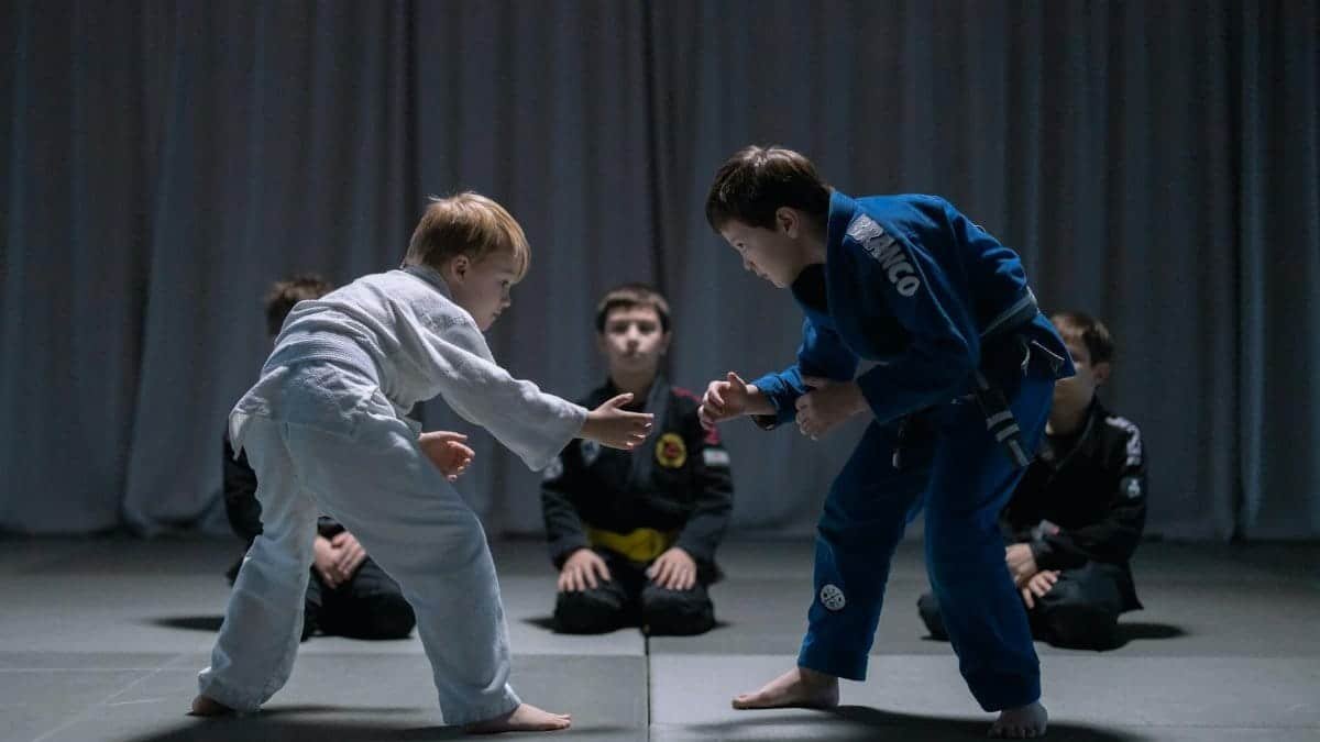 Children engage in martial arts practice, wearing traditional uniforms on a dojo mat.