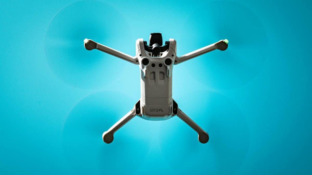 Aerial view of a drone flying against a vibrant blue sky, showcasing modern technology.