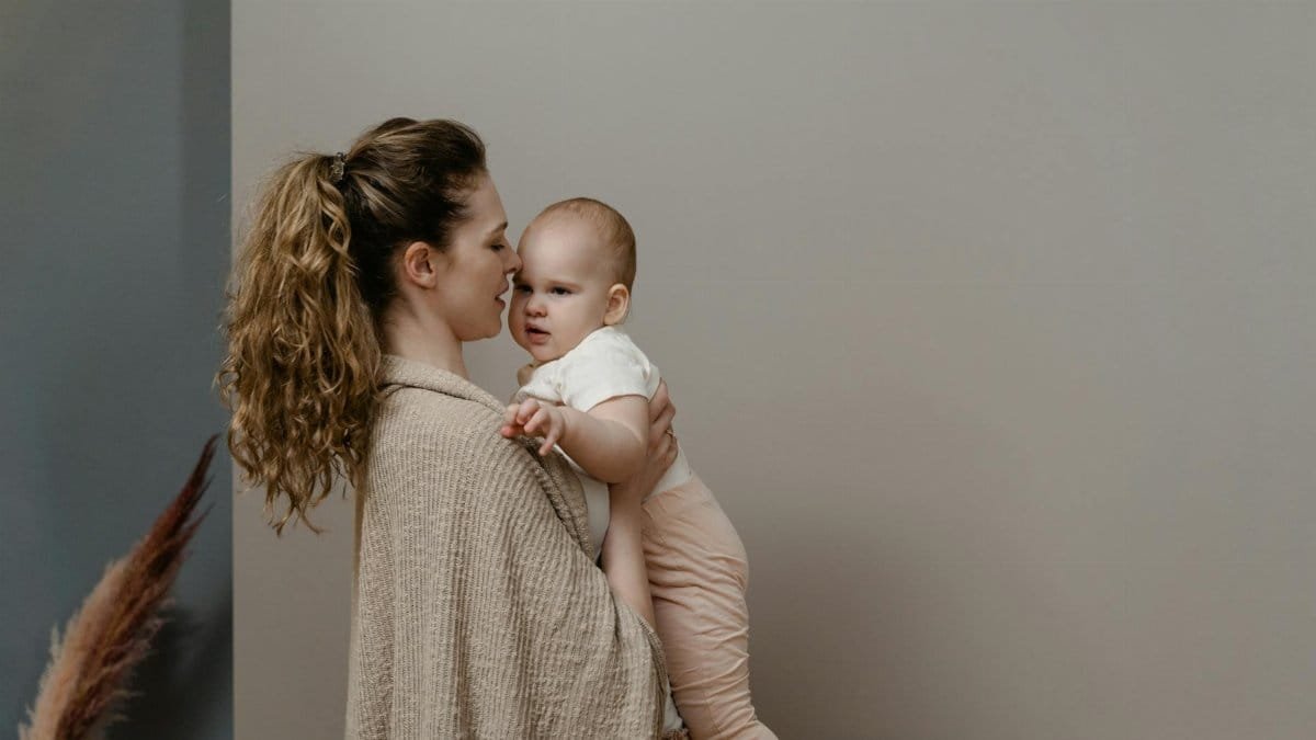 A mother lovingly holds her baby in a serene home interior, exuding warmth and care.